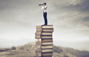 Man standing on pile of books looking through spyglass